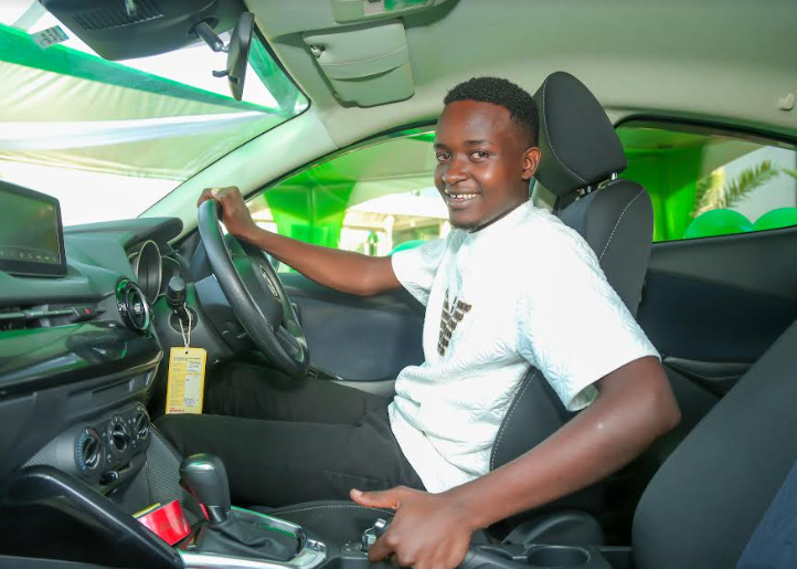 AL Mitaki Onchiri, the Safaricom Challenge Arena grand prize winner, poses for a picture with his brand-new vehicle.