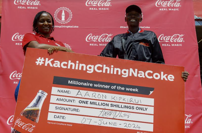 Winnie Maina, CCBA-Kenya Regional Sales Manager, hands over the dummy cheque to Aaron Kipkirui, the second millionaire in the Kachingching na Coke Promotion in Chepseyon Market, Kericho County.